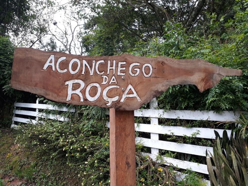 Placa de madeira entalhada com o nome Aconchego da Roça na entrada da pousada